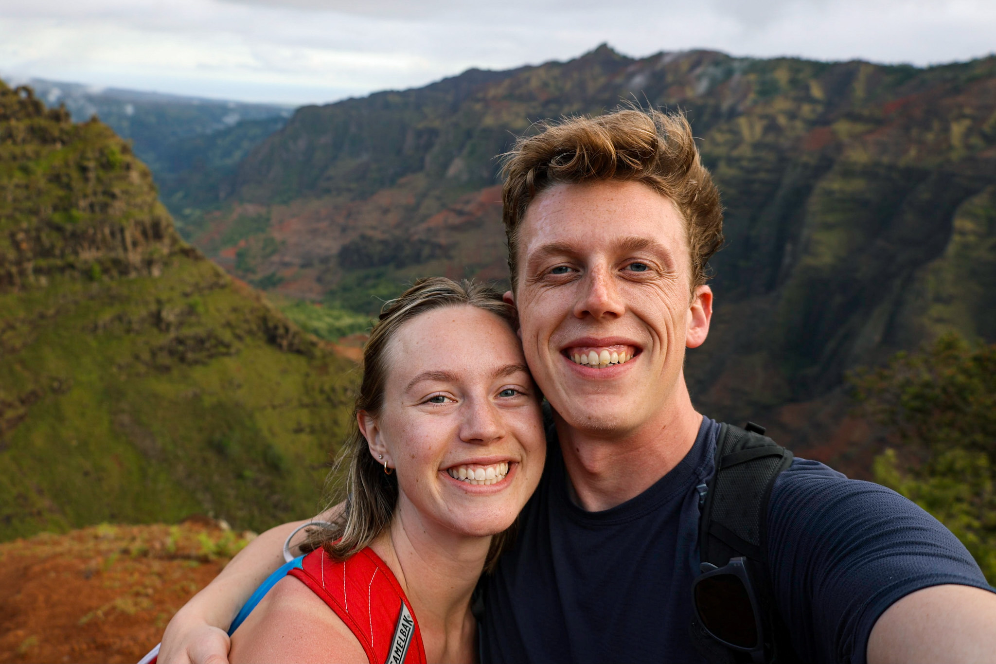 Sierra and Ridley smiling in a selfie with a green and red mountain canyon behind them